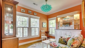 A room with large windows, a white cabinet, a floral sofa, and a round rug.