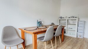 A dining area with a wooden table, four grey chairs, and a white cabinet with shelves.