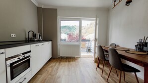 A modern kitchen with white cabinets, a built-in oven, and a dining area with a wooden table and chairs.