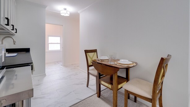 A dining area with a table set for two, a kitchen counter, and a view into another room. - Dock Access: Waterfront Studio in Colonial Beach! (Colonial Beach)