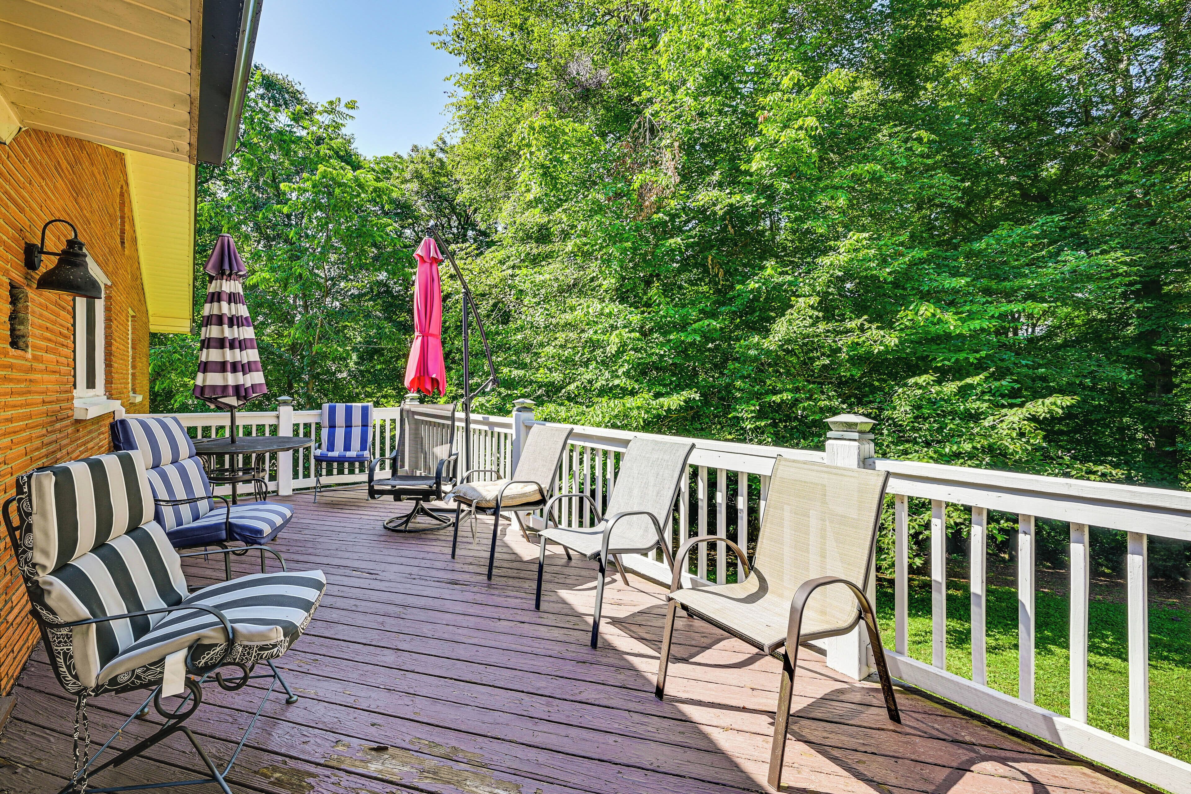 A wooden deck with outdoor furniture, including striped sofas and chairs, and a table.