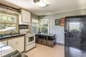 Una cocina con armarios blancos, un refrigerador de acero inoxidable y una ventana con persianas.