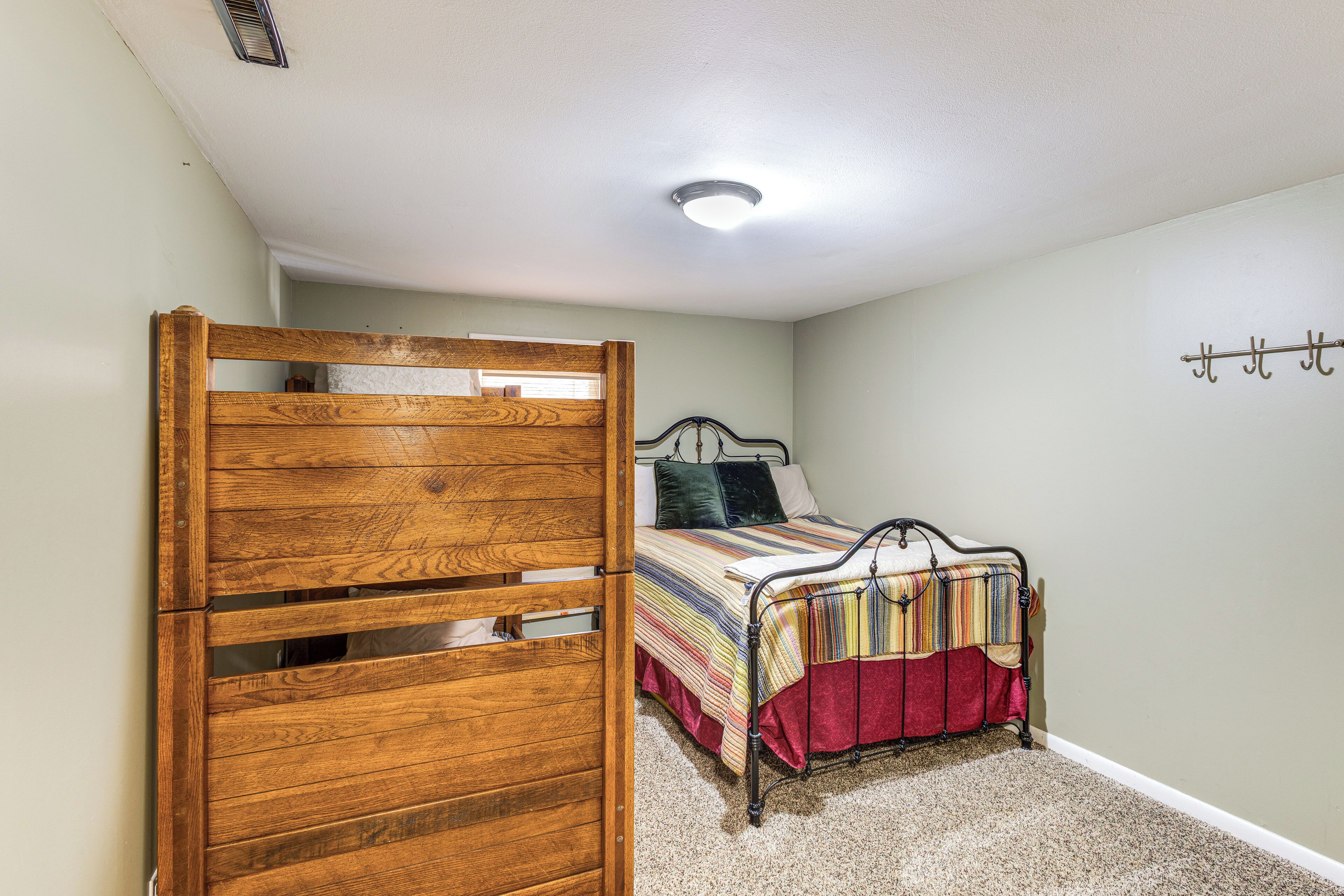 A bedroom with a wooden wardrobe, a bed with a striped bedspread, and a ceiling light.