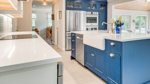 A modern kitchen with white countertops, stainless steel appliances, and blue cabinetry. - Pool, Gardens & Hot Tub: Luxe Sandy Hook Home! (Sandy Hook)