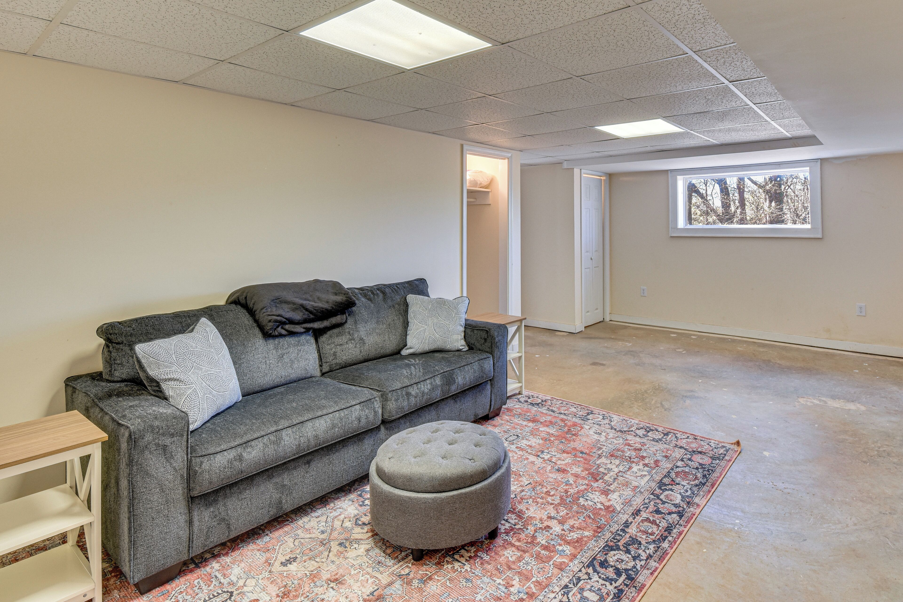 A living room with a grey sofa, ottoman, and patterned rug.