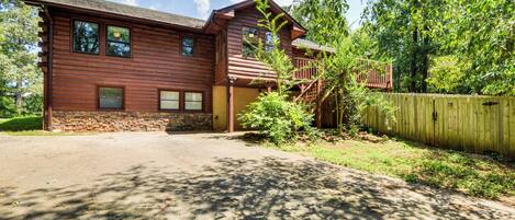 A two-story wooden house with a stone foundation, a front porch, and a wooden fence.