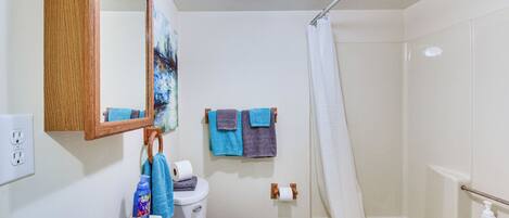 A bathroom with a white sink, toilet, and bathtub. There are towels hanging on the wall, a mirror, and a shower curtain.