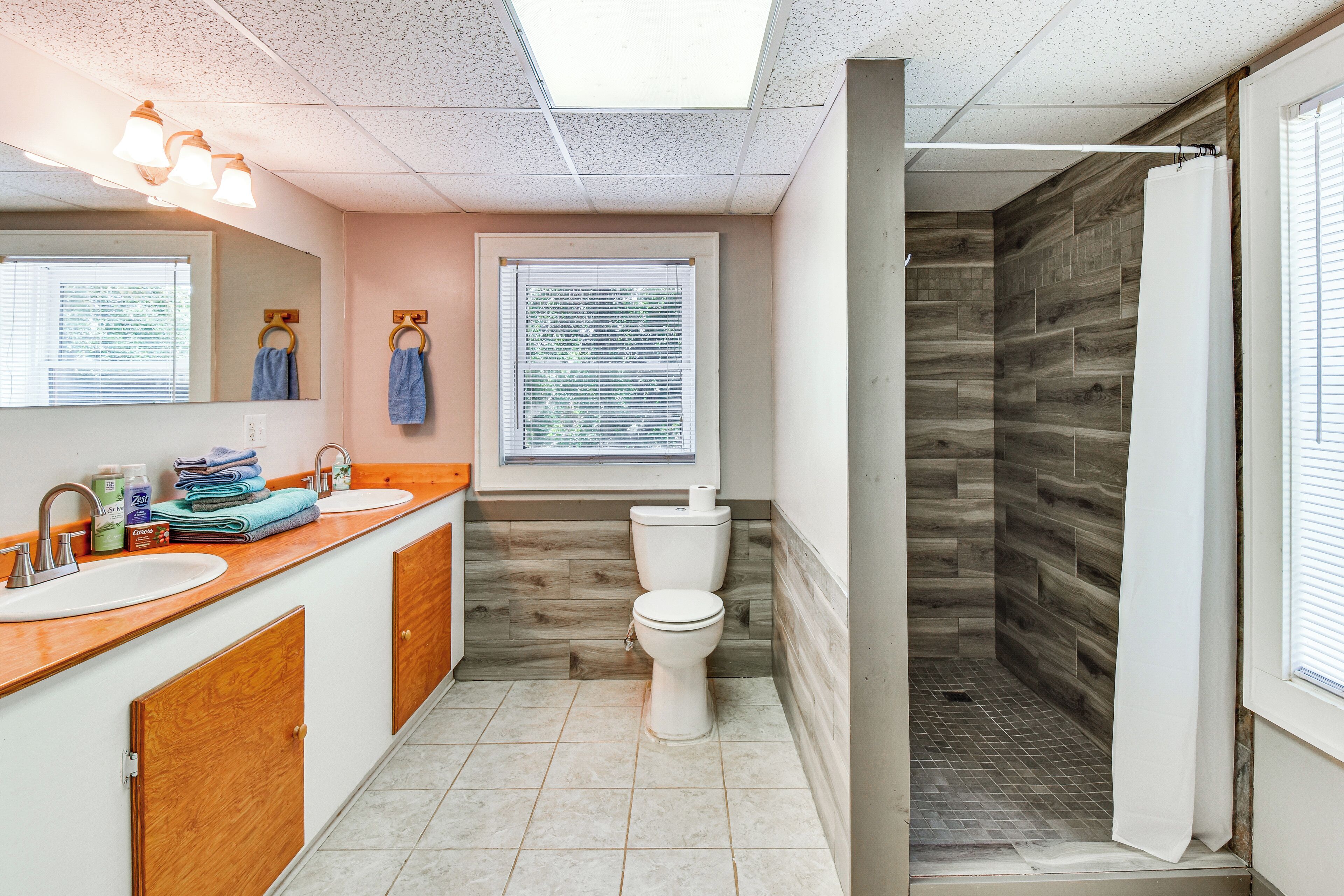Une salle de bain avec un mur de douche en bois, des toilettes et un lavabo avec un miroir au-dessus.