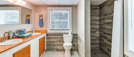 Une salle de bain avec un mur de douche en bois, des toilettes et un lavabo avec un miroir au-dessus.