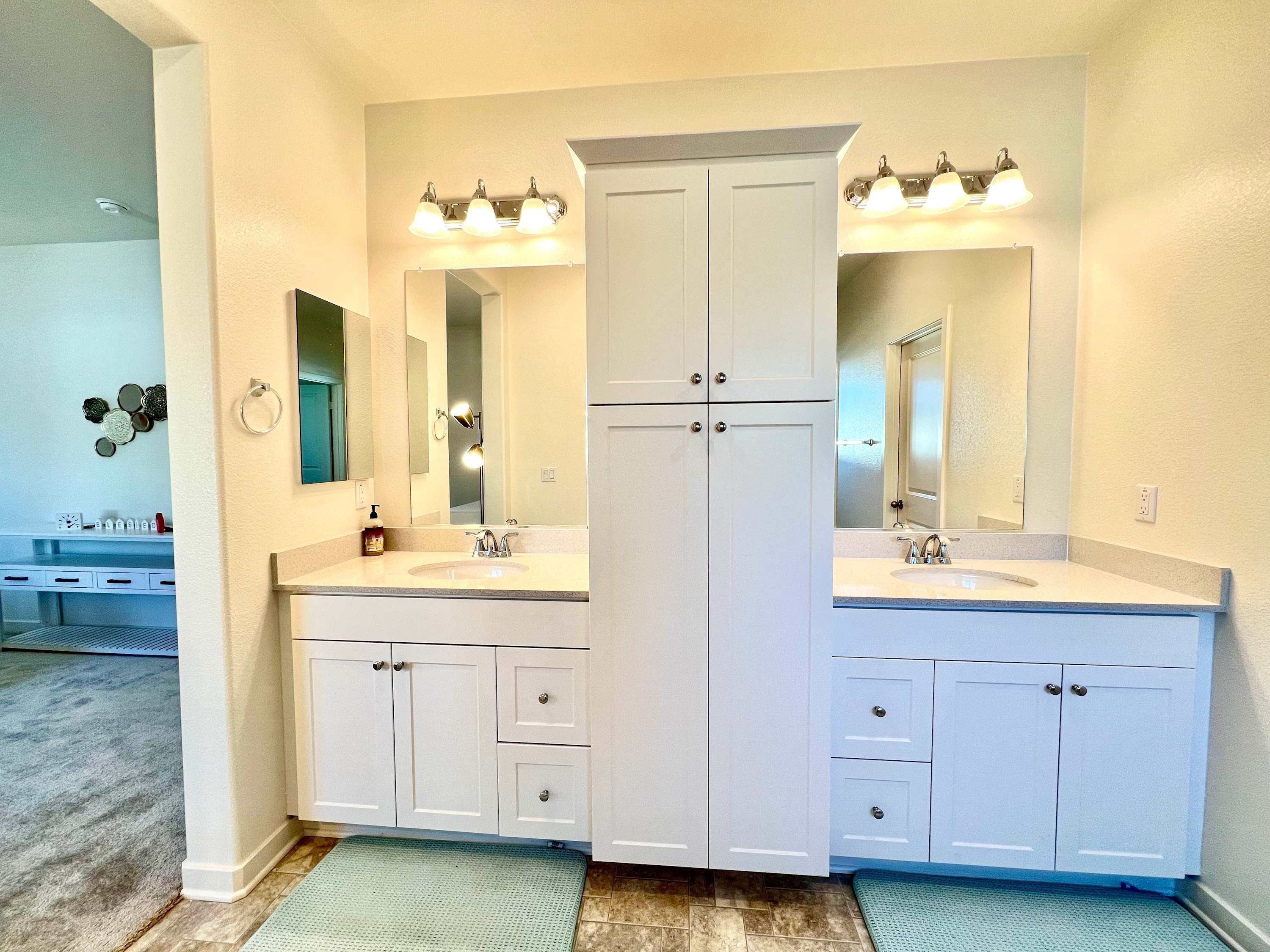 A bathroom with a double sink vanity, a large mirror, and a cabinet with drawers.