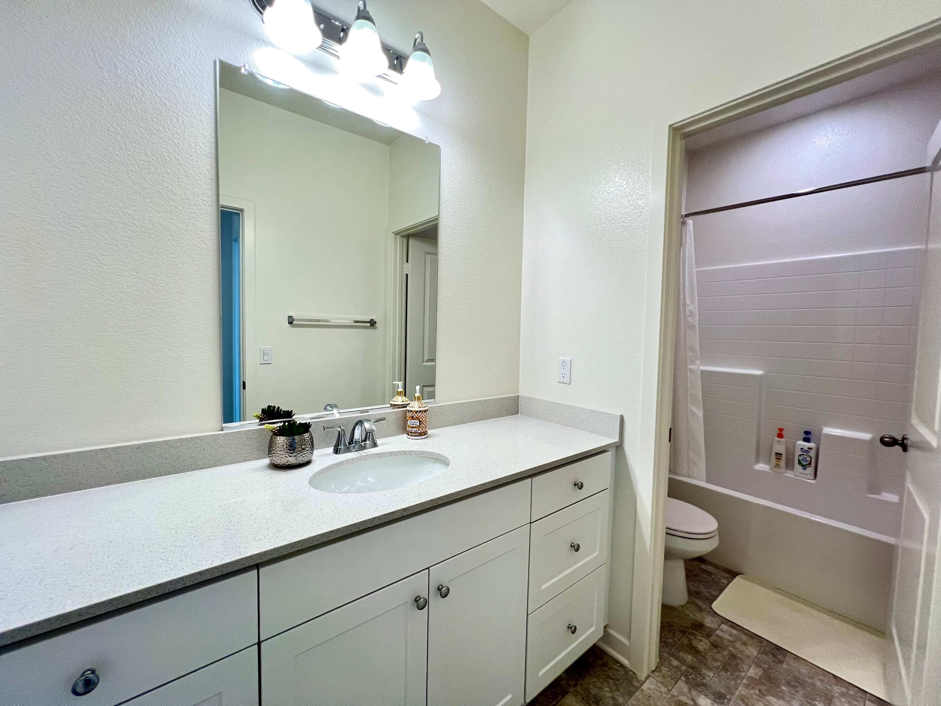 Un baño con lavamanos blanco, un espejo y un inodoro.