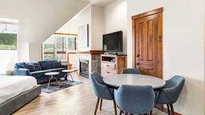 A modern living room with a sofa, a dining table with chairs, a fireplace, and a television. - Top Floor Studio! Peak 9 base/Main St, 7 Hot Tubs (Breckenridge)