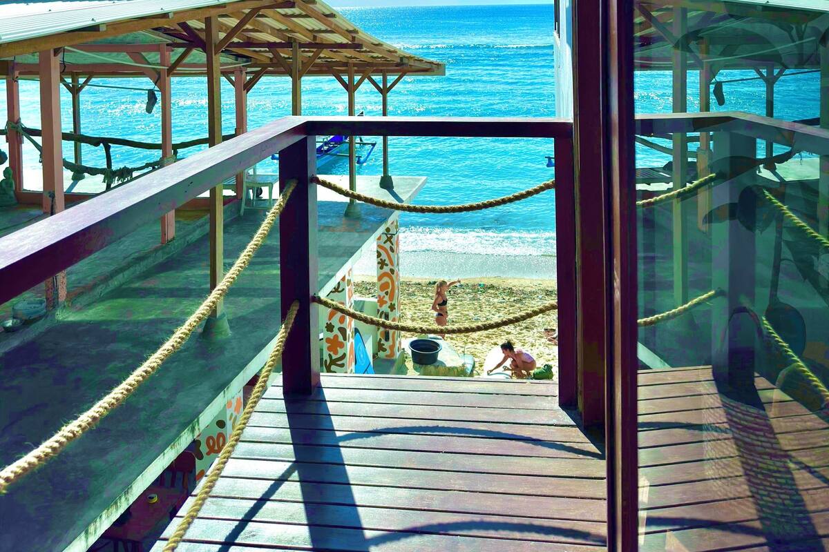 A wooden deck with a rope barrier overlooking a beach and the ocean.