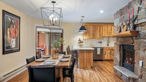 Een moderne keuken met houten kastjes, een stenen openhaard en een eethoek met een houten tafel en stoelen.