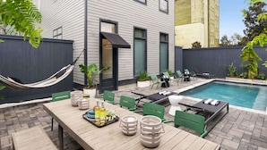 A modern outdoor pool area with a wooden table, chairs, and a hammock. - Spacious NOLA Combo, 2 Units & Shared Pool (New Orleans)