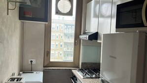 Eine kleine Küche mit Fenster, Mikrowelle, Herd und Toaster.