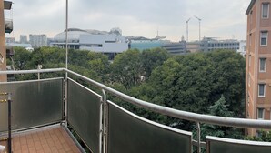 Ein Balkon mit Blick auf eine Stadtansicht, darunter moderne Gebäude und eine Baustelle.