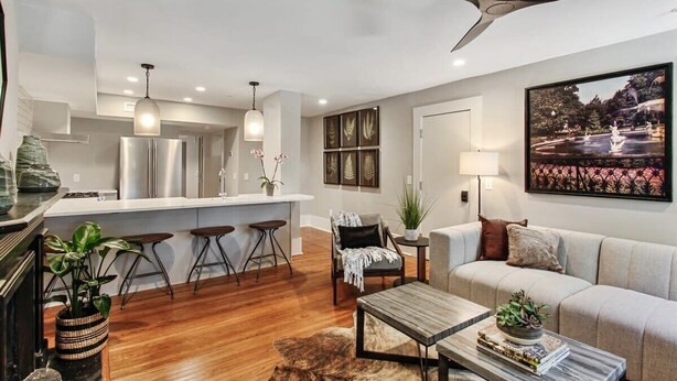 A modern living room with a sofa, coffee table, and a dining area with bar stools. - Cozy 1BR Historic Condo | Downtown Savannah (Savannah)