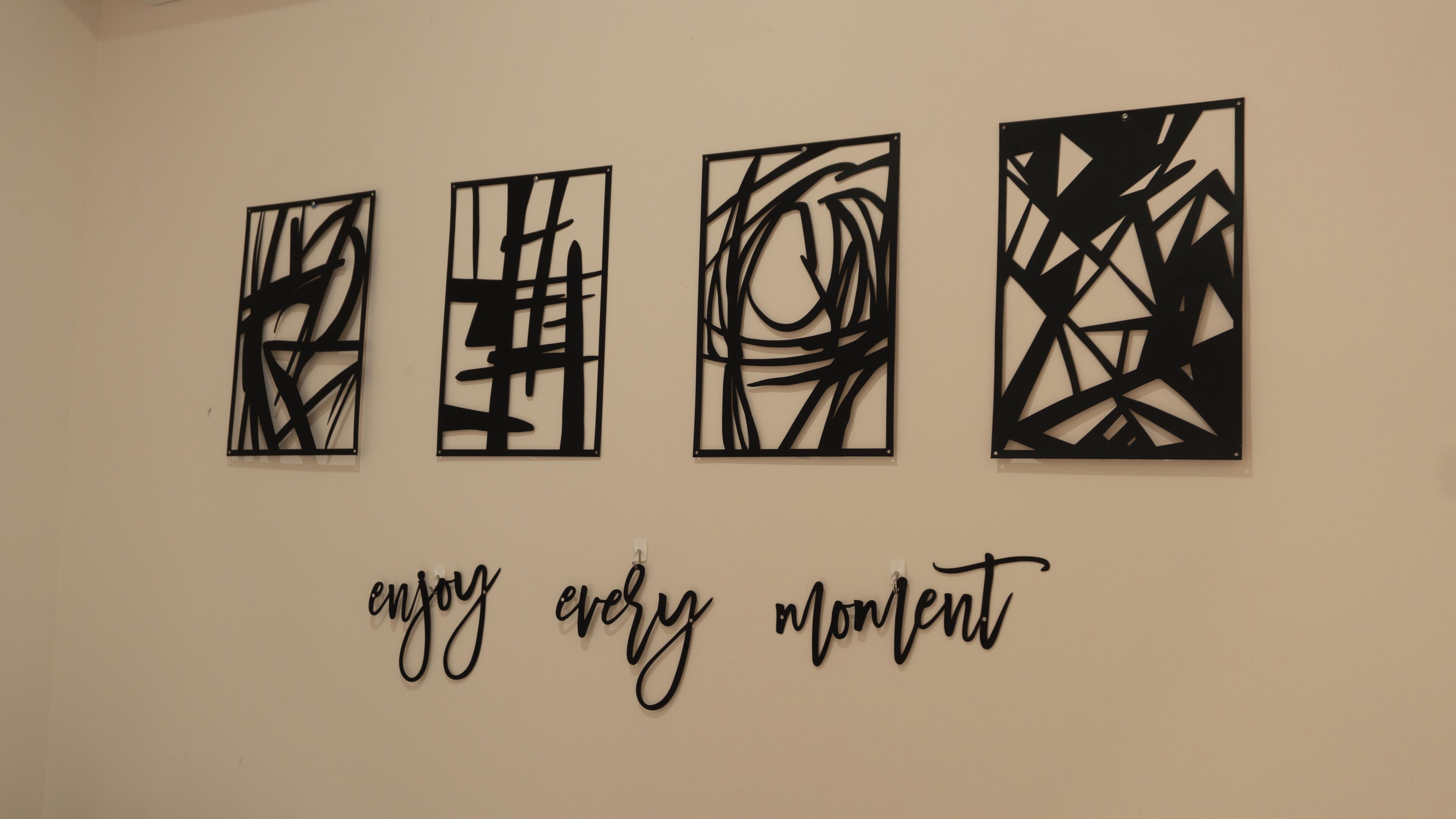 Quatre œuvres d’art abstrait sont accrochées à un mur, et une phrase inspirante figure en dessous.
