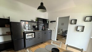 A modern kitchen with a built-in oven, a refrigerator, and a dining area with a wooden table and chairs. - Cozy vacation apartment in the heath (Hodenhagen)