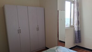 Une chambre à coucher avec un lit, une armoire et une fenêtre avec des rideaux.