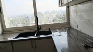 Une cuisine dotée d’une grande fenêtre, d’un évier en acier inoxydable et d’un plan de travail en marbre.