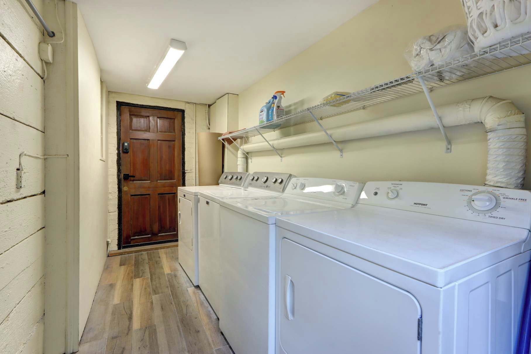 A laundry room with a washing machine, dryer, and shelves with laundry supplies.