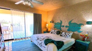 A bedroom with a bed, a nightstand, a lamp, a wall mural, and a view of the outside.