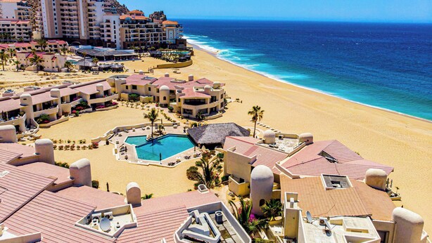 Een resort met meerdere gebouwen, een strand en een zwembad.