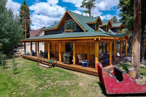A cabin with a porch, outdoor seating, and a grill.