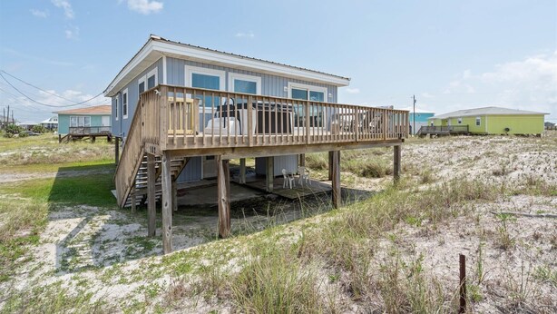 A beachfront house with a wooden deck and a covered porch. - Dauphin Island Escape - 102 Ponchartrain Ct 3 Bedroom Home (Dauphin Island)