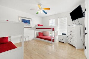 A room with bunk beds, a ceiling fan, a TV, and a dresser. - Treasure Island - 105 Treasure Ct 4 Bedroom Home (Dauphin Island)