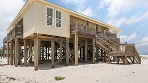 Ein Strandhaus mit einer Holzterrasse und einer Treppe zum Eingang.