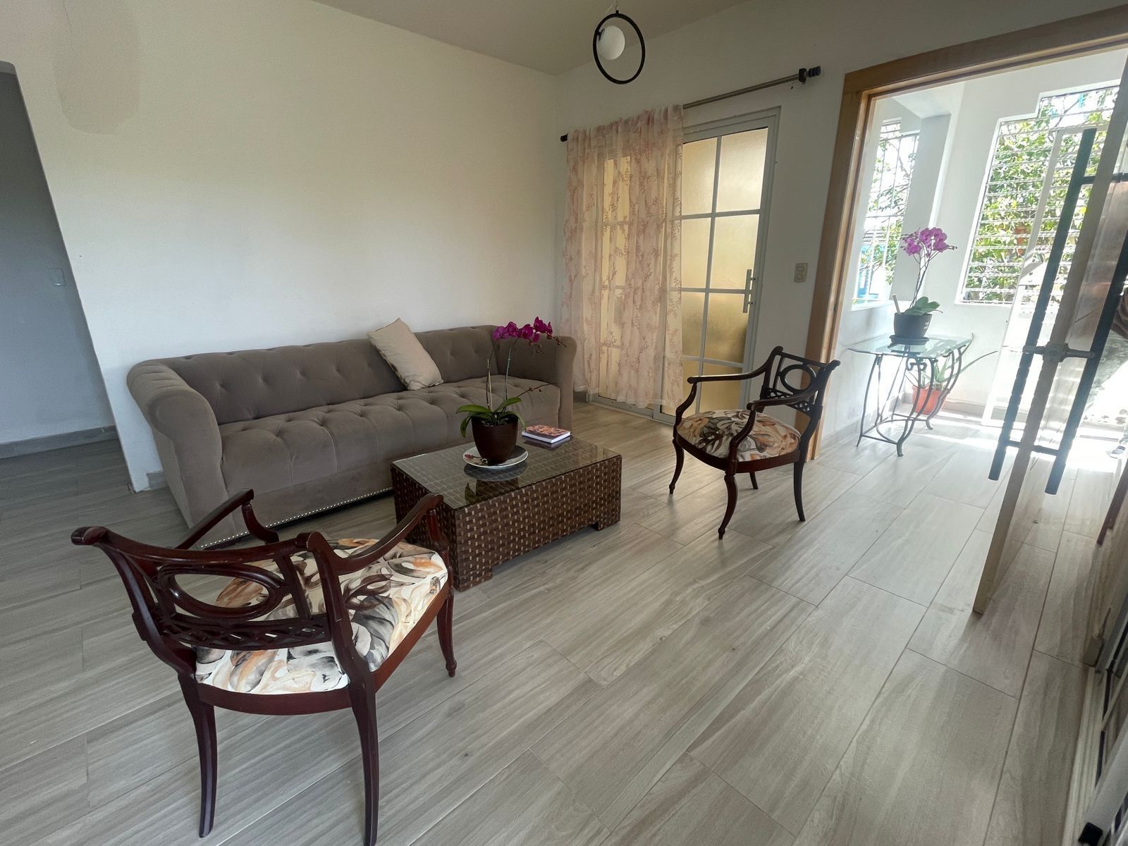 Una sala de estar con un sofá, dos sillones, una mesita de centro y una planta en maceta.