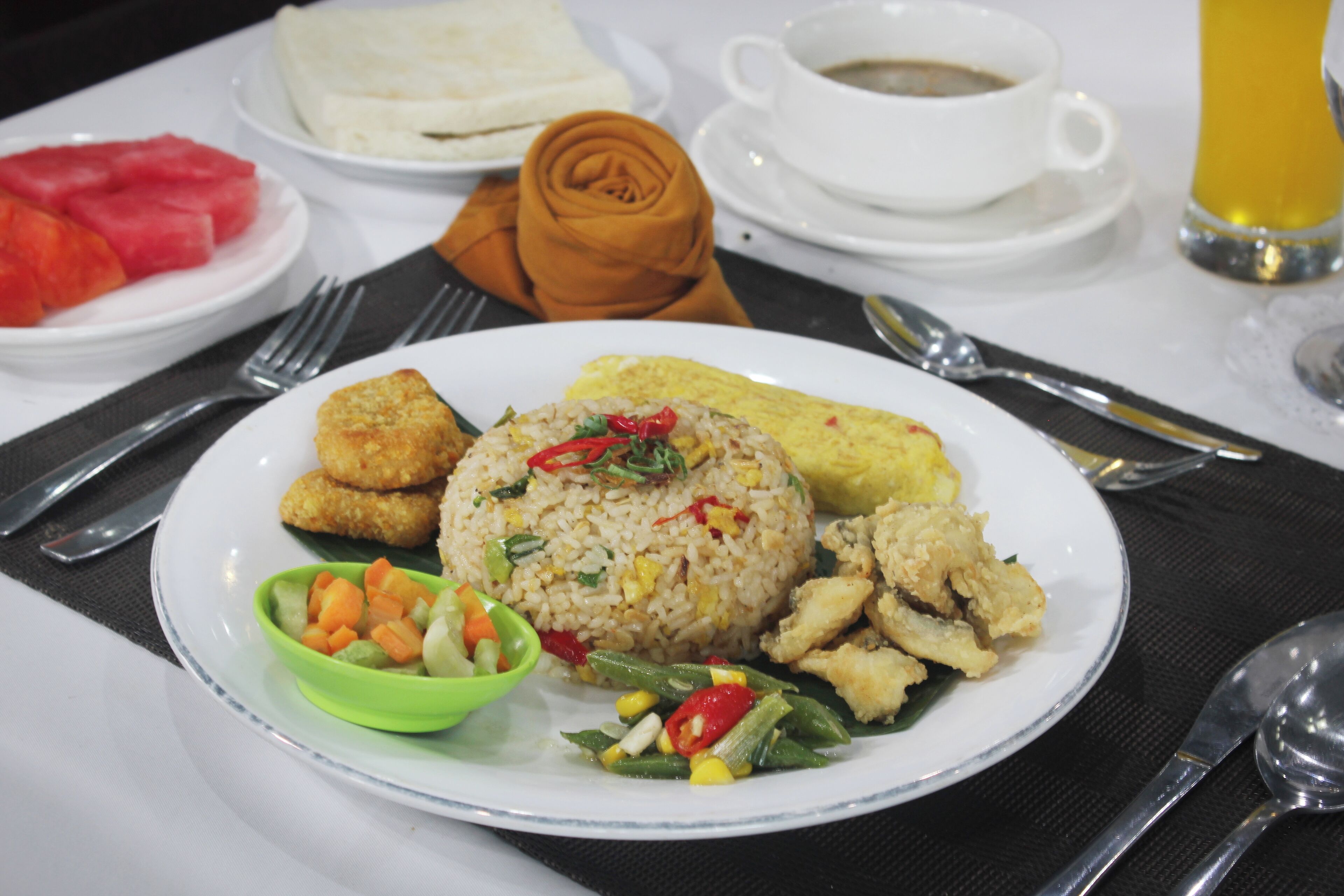 A plate of fried rice with vegetables and a side of soup.