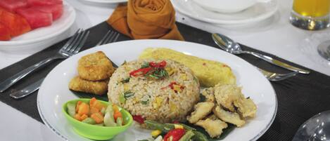 A plate of fried rice with vegetables and a side of soup.