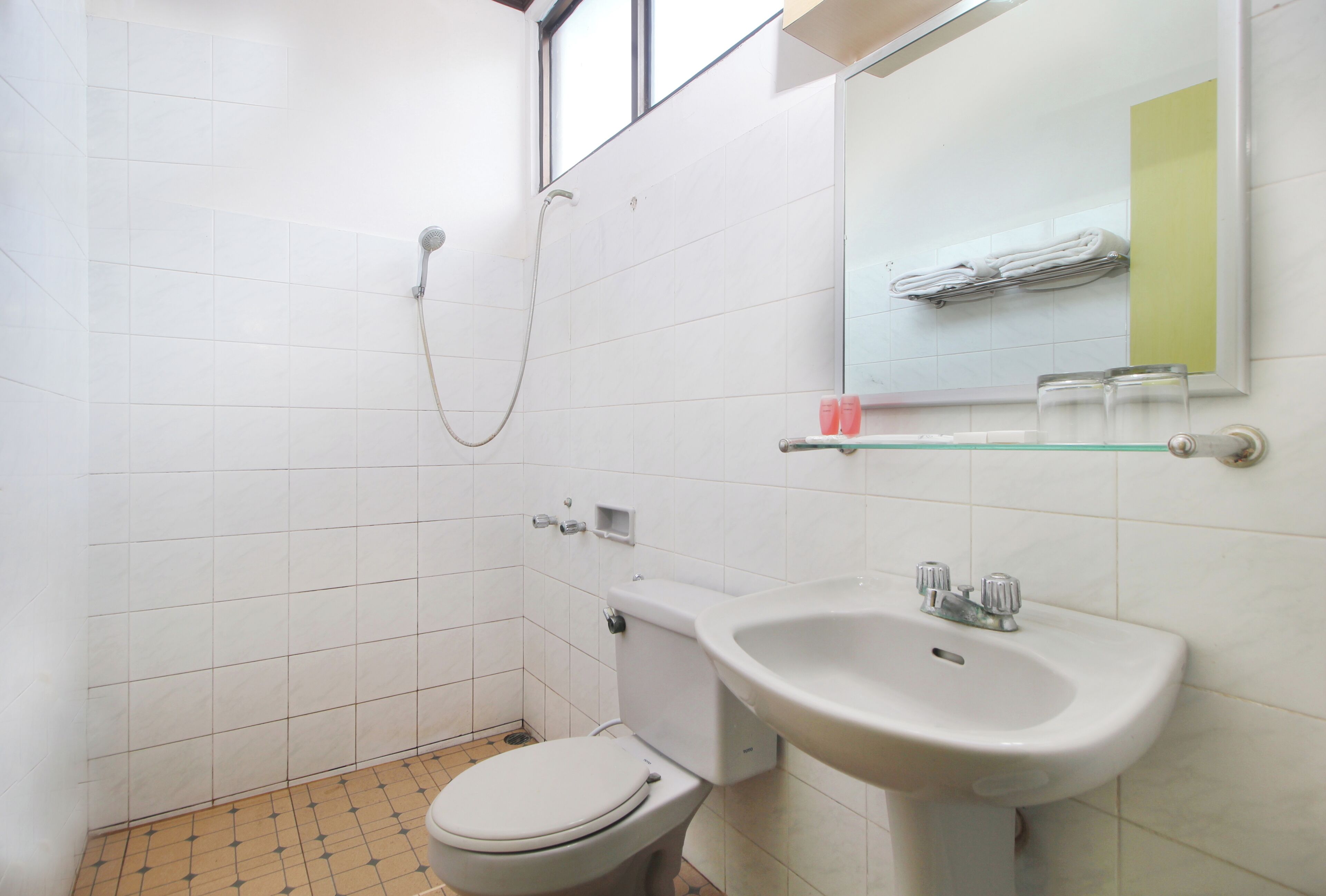A small bathroom with a toilet, sink, and shower.