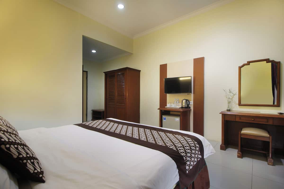 Une chambre d’hôtel avec un lit, une commode en bois, une télévision et un miroir.
