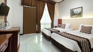 Quarto de hotel com duas camas, uma mesa de trabalho com cafeteira, televisão e um quadro na parede.