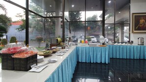 Disposição de buffet com diversos alimentos e toalha de mesa azul.