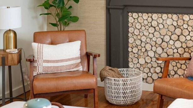 Una sala de estar acogedora con chimenea, una planta, una cesta tejida y una mesa de centro con un cuenco y una cuchara.