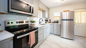 Una cocina moderna con electrodomésticos de acero inoxidable, armarios blancos y piso de madera clara.