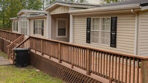 A row of mobile homes with a wooden deck and a grassy yard.