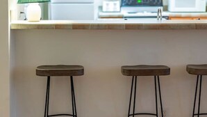 A kitchen with a white countertop, a green lamp, and three stools.