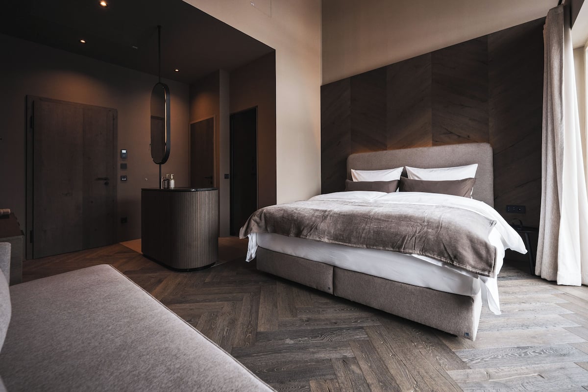 Une chambre à coucher moderne avec un grand lit, une commode et un miroir.