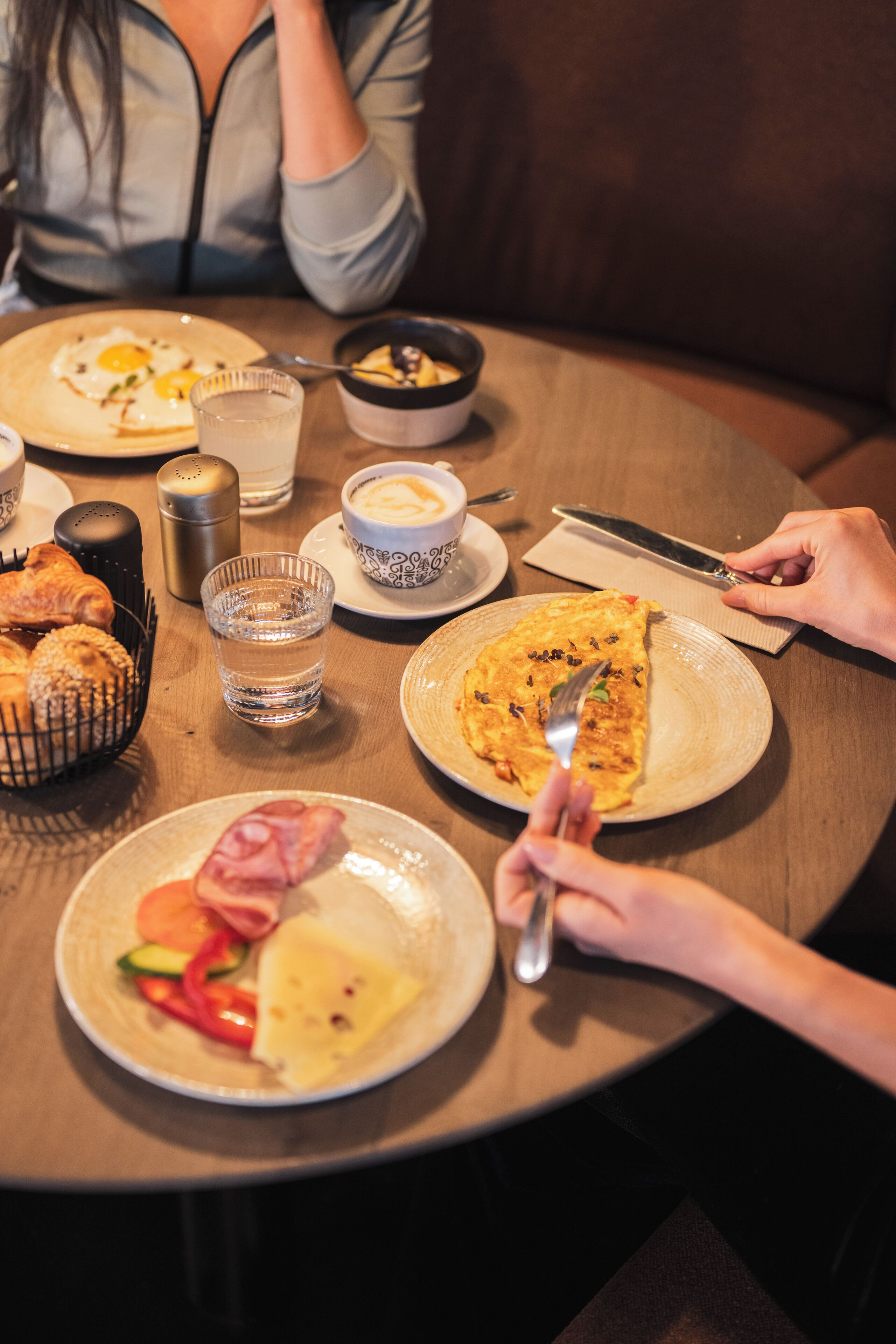 A round dining table with plates of food, a glass of water, and a salt shaker.