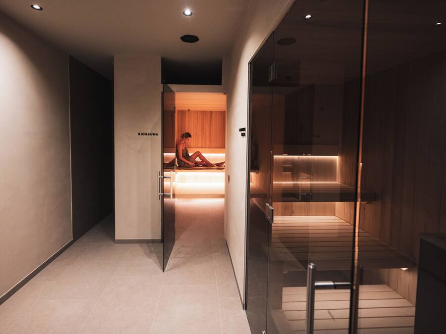 A modern hotel corridor with a visible spa area, a reception desk, and a glass partition.