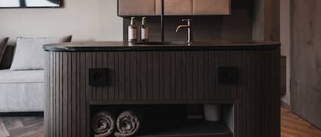 A modern bathroom with a wooden vanity, a mirror with a glowing frame, and a built-in towel rack.