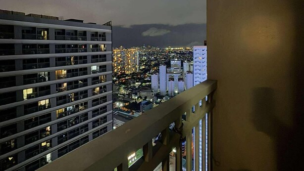 A high-rise building with multiple floors, large windows, and a view of a cityscape at night. - Relaxing City Retreat (Mandaluyong City)