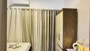 A modern bedroom with a bed, a desk, a chair, and an air conditioning unit. - Relaxing City Retreat (Mandaluyong City)